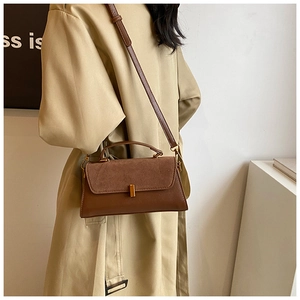 Detail of a brown PU suede shoulder bag featuring a gold metal buckle and contrast panels