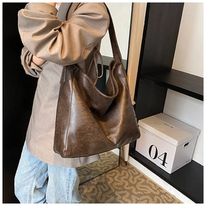 Detailed view of large dark brown leather tote bag styled with a grey blazer and jeans