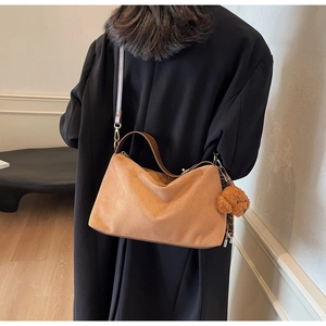 Detailed view of brown PU leather shoulder bag with cute teddy bear charm on model