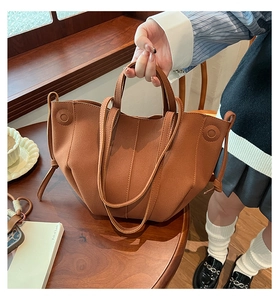 Detailed view of brown PU leather tote bag with stitch stitching and stylish side drawstring