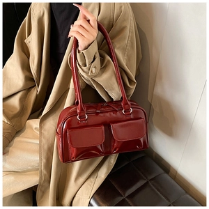 Detail of glossy deep red faux leather shoulder bag with two front pockets
