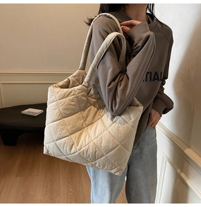 Detail shot of the beige quilted fabric texture and wide shoulder strap on tote bag