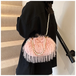 Detailed shot of pink plush shoulder bag with pearl strap and fringe tassels on model