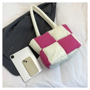 Flat lay of pink and white checkered quilted nylon tote bag with gadgets on white fabric