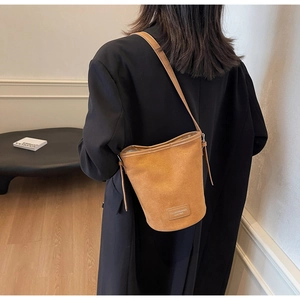 Close-up of the vintage brown suede bucket bag with adjustable strap and designer leather tag