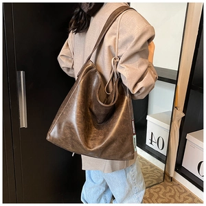 Detail of dark brown vintage PU leather tote bag with stylish side label shown on a model