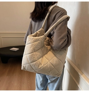 Detail view of beige quilted tote bag showing padded texture and wide shoulder strap