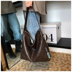 Detailed shot of large brown PU leather tote bag with vintage texture and brand label