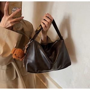 Detail of dark brown faux leather shoulder bag with cute plush bear charm accessory