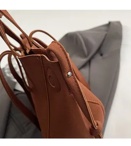 Detail of brown faux suede shoulder bag showing round stitching and silver metal rivet