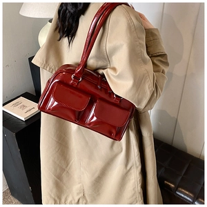 Detailed side view of a dark red patent leather shoulder bag with silver hardware accents