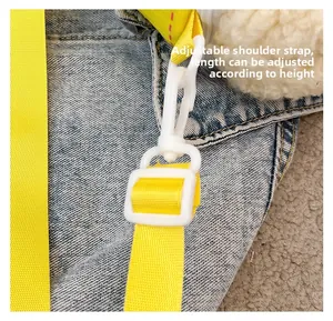 Detail of adjustable yellow woven strap with plastic buckle on blue denim bag