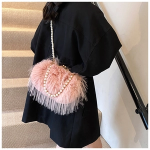 Detail of pink plush shoulder bag featuring elegant pearl chains and soft faux fur texture