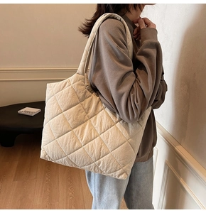 Quilted beige tote bag with a soft texture shown on a model in a minimalist setting