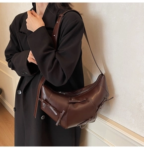 Détail du sac croissant marron foncé avec nœuds et bandoulière en cuir réglable