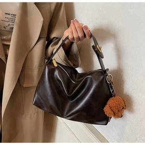 Detail of soft dark brown PU leather hobo bag with a cute plush dog charm accessory
