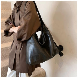 Close-up of a black matte PU leather tote bag with a wide strap on woman shoulder