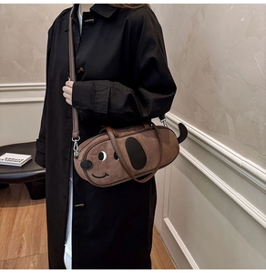 Gros plan du sac bandoulière marron en forme de teckel porté sur un manteau noir