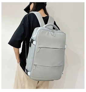 Rear view of light grey travel backpack with multiple zippers and side compression straps