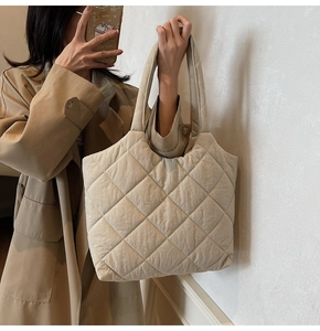Detail of a beige quilted tote bag showing wide straps and soft nylon fabric texture