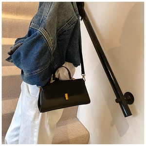 Minimalist black PU matte crossbody bag with gold metal buckle shown on shoulder