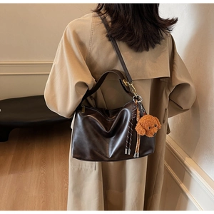 Detail of soft dark brown PU leather shoulder bag with a cute teddy dog plush charm accessory