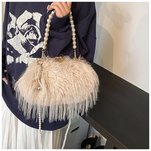 Detail of plush apricot shoulder bag with pearl handle and heart bow pendant charm