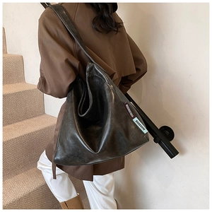 Close-up of minimalist brown faux leather shoulder bag showing texture and fabric label