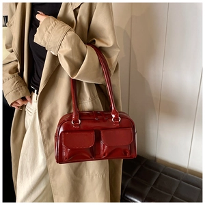 Detail view of a vintage glossy burgundy shoulder bag with dual front flap pockets