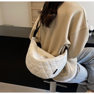 Detailed back view of a white quilted crescent shoulder bag with adjustable strap