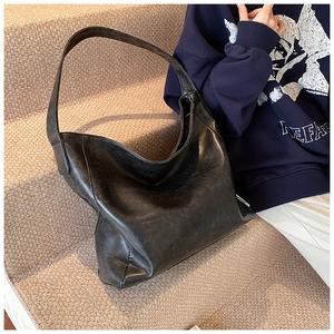 Detail of a large black PU hobo bag with vintage texture and brand label on a felt step