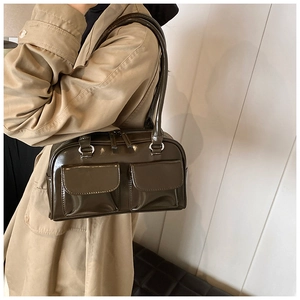 Detail of dark olive green patent leather shoulder bag with symmetrical front pockets