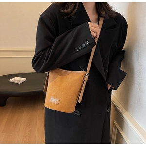 Detail view of the brown matte PU leather bucket bag with adjustable shoulder strap and tag