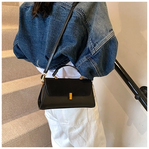 Chic black crossbody bag with matte flap and gold buckle shown on a staircase