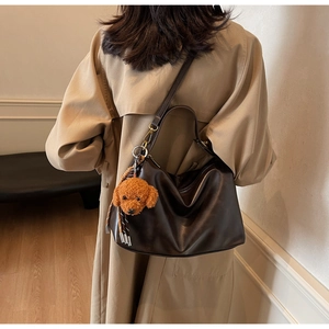 Detail of dark coffee leather crescent shoulder bag with brown plush puppy charm