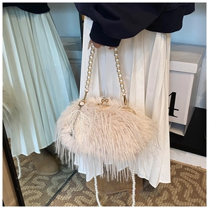Macro detail of plush faux fur shoulder bag featuring elegant pearl handle and bow