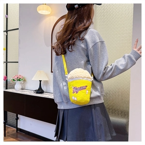 Popcorn-shaped plush crossbody bag worn by a model in a cozy indoor lifestyle setting