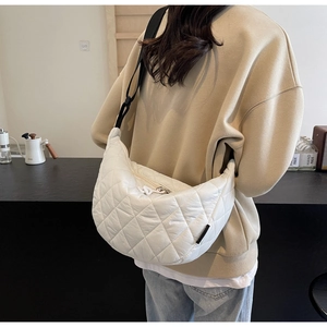 Detail of white quilted crescent bag with adjustable strap and textured stitching