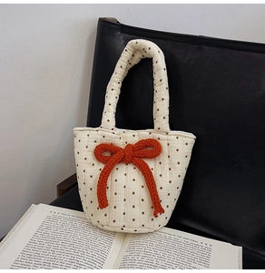 Detail of quilted cotton tote bag featuring brown polka dots and orange rope bow ornament