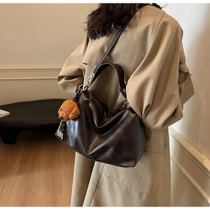Detail of soft dark brown PU leather hobo bag with teddy bear plush charm accessory