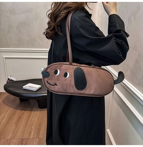 Détail d'un sac bandoulière marron en forme de teckel porté par un mannequin en studio