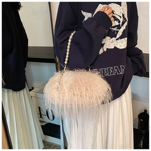 Detailed shot of beige plush fur handbag with elegant pearl handle and bow charm
