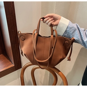 Detail view of brown PU leather tote bag with tassels on a wooden chair