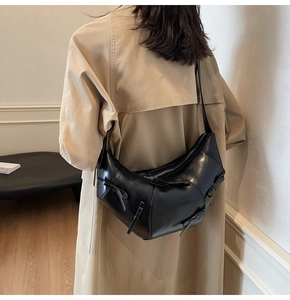 Détail du sac porté épaule noir en similicuir en forme de croissant avec des nœuds décoratifs