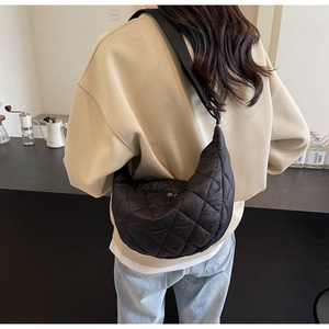 Detail of black quilted nylon crescent crossbody bag with adjustable wide strap on model