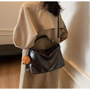 Close-up of matte dark brown PU leather crescent shoulder bag with a teddy dog pendant