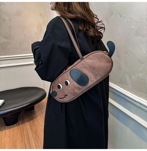 Détail du sac à bandoulière marron en forme de chien porté sur manteau noir