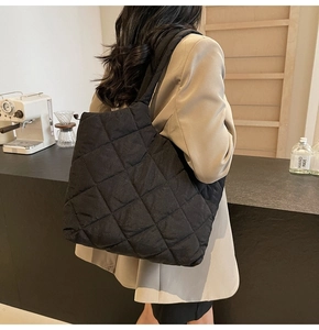 Detailed view of black quilted puffer tote bag on shoulder for modern commuting style