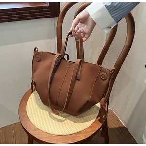 Detailed view of caramel PU leather tote bag with textures on a wooden chair