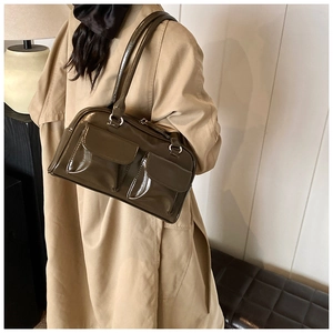 Detail of a vintage dark olive green patent leather shoulder bag with glossy finish and pockets